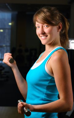 Beautiful woman is exersising in gym at evening clipart