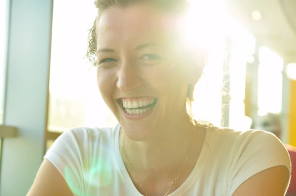 Sehr glückliche Frau sitzt im Café und blickt in die Kamera — Stockfoto