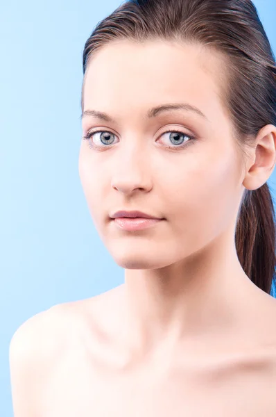 Portrait of a young beautiful woman looking at camera, on blue b — Stock Photo, Image
