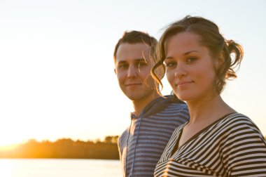 young attractive couple is walking near lake at sunset