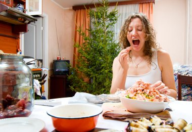 young woman is cooking holiday food and tasting it clipart