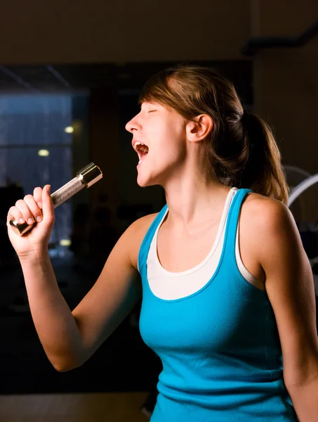 苗条的女人在唱晚上健身房 Usian 杠铃作为一个麦克风 — 图库照片