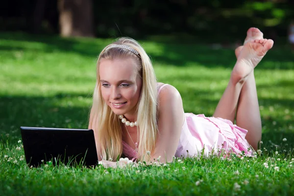 Park yerinde dizüstü bilgisayar kullanan genç bir kadın — Stok fotoğraf