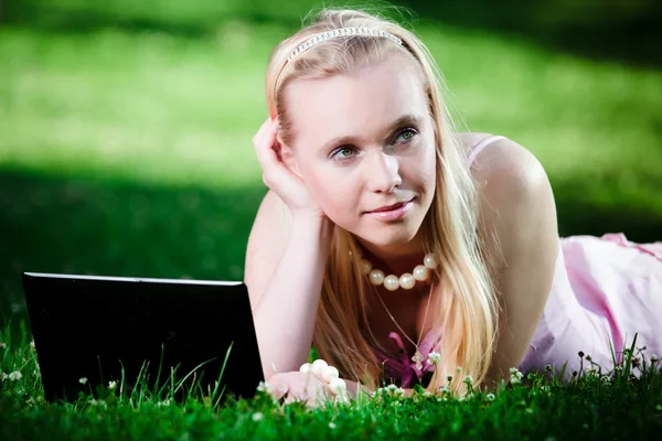 Ung kvinna som använder laptop i parken — Stockfoto