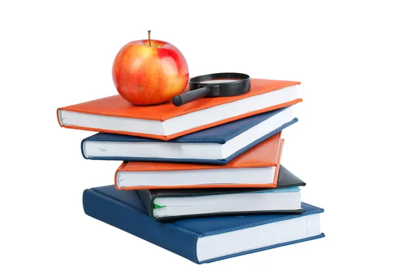 Magnifying glass and red apple on stack of books — Stock Photo, Image