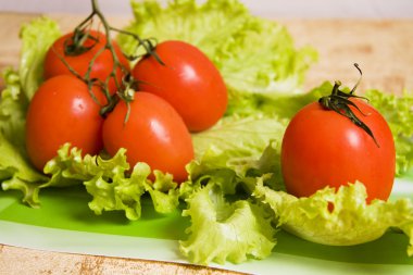 Branch of tomatos. Group red tomatos on leaf lettuce. clipart