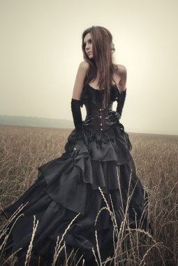 Young goth woman walking on field.