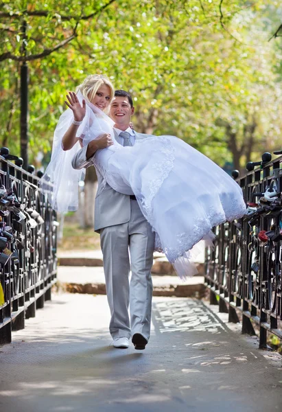 橋の上を歩く若い結婚式のカップル — ストック写真