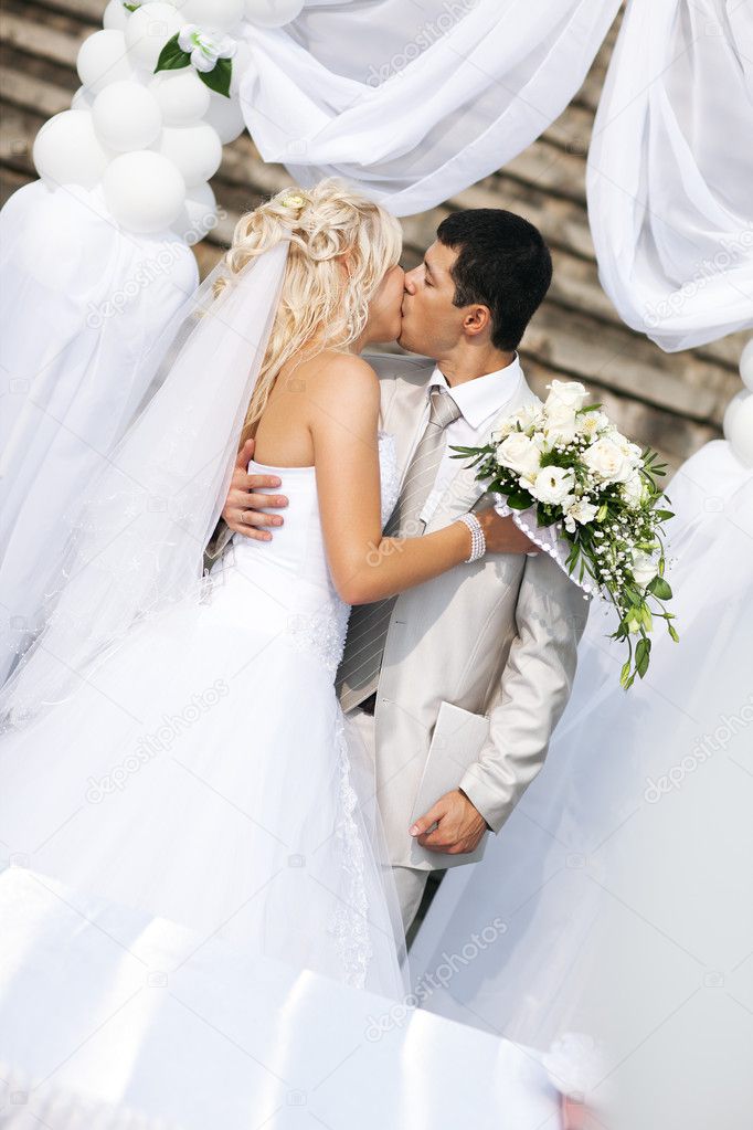 Young wedding couple kissing. White colors.