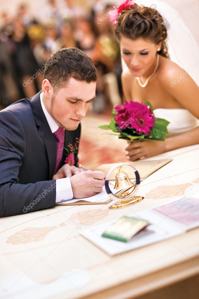 Young couple signing wedding documents