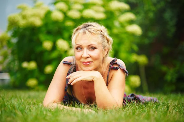 Öğleden sonra bir çim için yalanlar üzerine ortalama yaş kadın — Stok fotoğraf