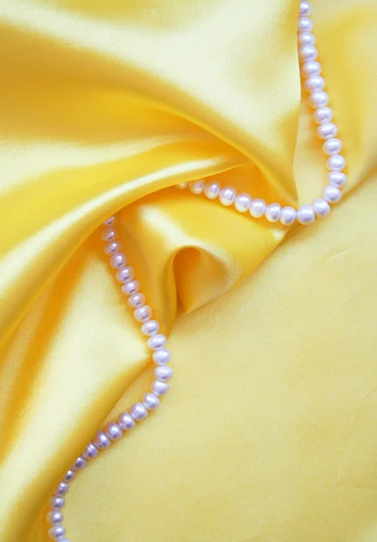 Smooth elegant golden silk with pearls — Stock Photo, Image