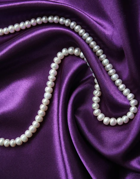 Vita pärlor på en lila siden som bakgrund — Stockfoto