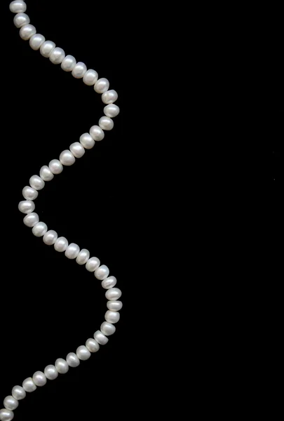 Білі перлини на чорному шовку як фон — стокове фото