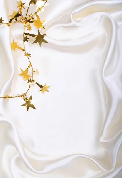 Estrelas douradas e lantejoulas na seda branca — Fotografia de Stock