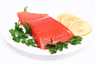 Salmon steak with lemon slices and parsley on white plate clipart