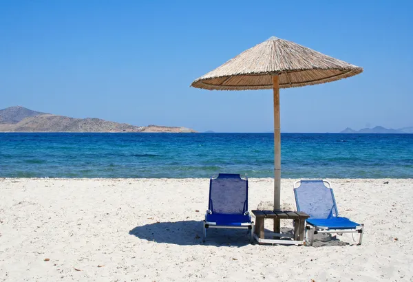 Grecja. Wyspa Kos. dwa leżaki i parasol na plaży — Zdjęcie stockowe