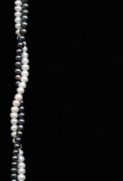 Perle bianche e nere sul velluto nero come sfondo — Foto Stock