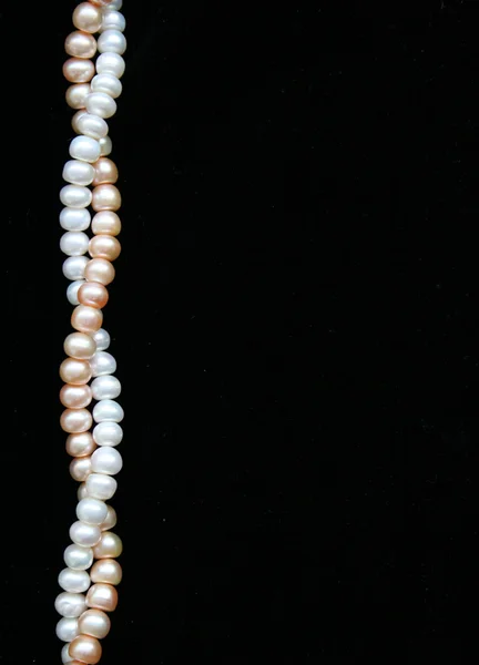 White and pink pearls on the black background — Stock Photo, Image