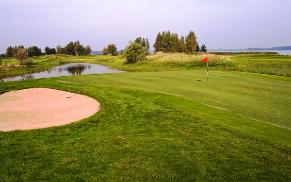 Поле для гольфа с небольшим озером — стоковое фото