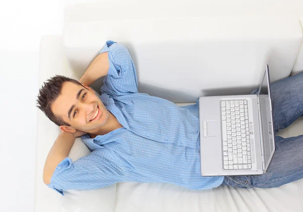 Πορτρέτο του ένας νεαρός άντρας χαλαρωτικό στον καναπέ με ένα laptop — Φωτογραφία Αρχείου