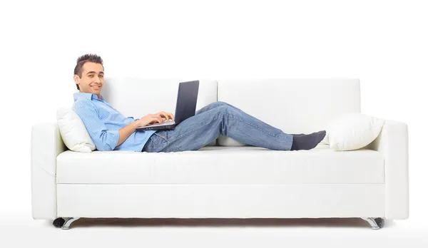 Uomo felice che lavora sul suo computer portatile sul divano di casa — Foto Stock