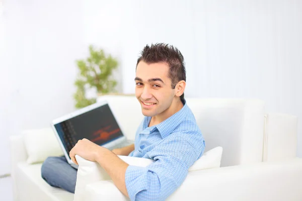 Szczęśliwy człowiek działa na jego laptopie na kanapie w domu — Zdjęcie stockowe