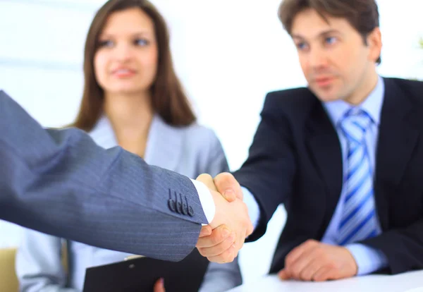 Двое бизнесменов пожимают друг другу руки, когда команда улыбается в офисе — стоковое фото