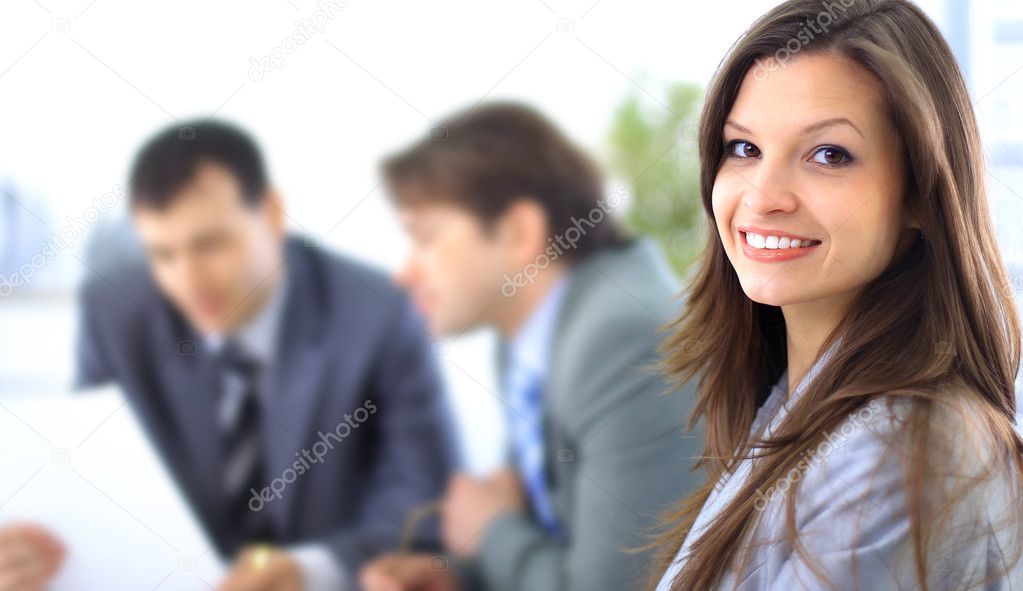 A confident relaxed business woman smiling with her colleagues at the back