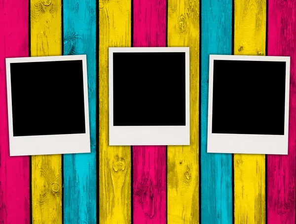 Três fotos em branco sobre fundo de madeira multicolorida — Fotografia de Stock