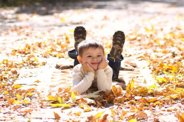 Child lying on the golden leaf clipart