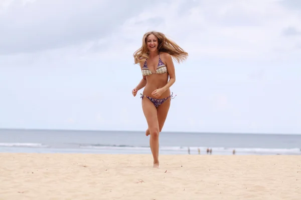 Glückliche Frau im Bikini spaziert am Strand — Stockfoto