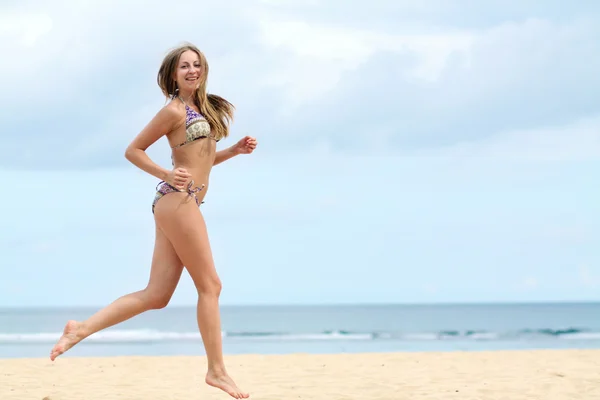 Femme heureuse en bikini marche sur une plage — Photo
