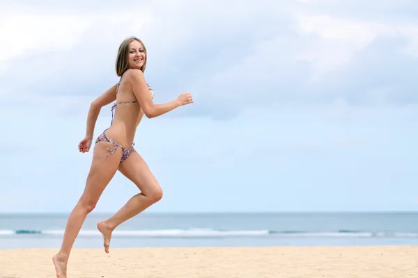 Mutlu bir kadın bikinili kumsalda yürür — Stok fotoğraf