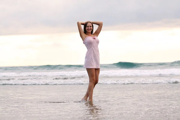 Mujer joven de pie en una playa y disfrutando del sol — Foto de Stock
