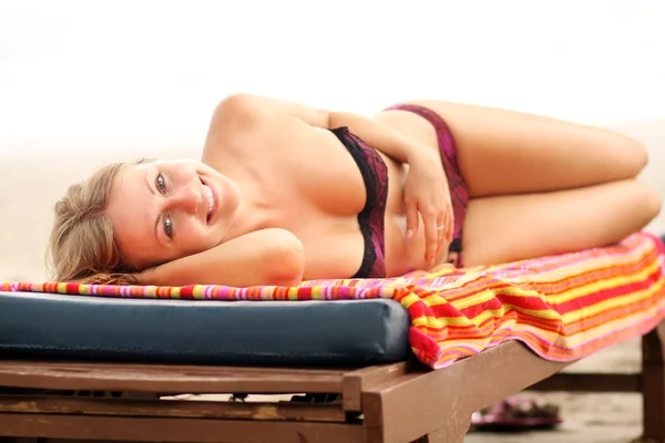Mulher banhos de sol deitado em salões de chaise — Fotografia de Stock
