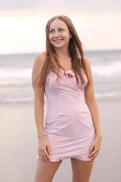 Junge Frau im rosa Kleid am Strand — Stockfoto