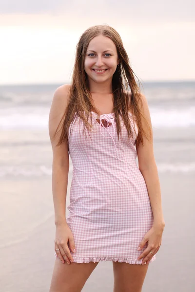 Mladá žena v růžových šatech na pláži — Stock fotografie