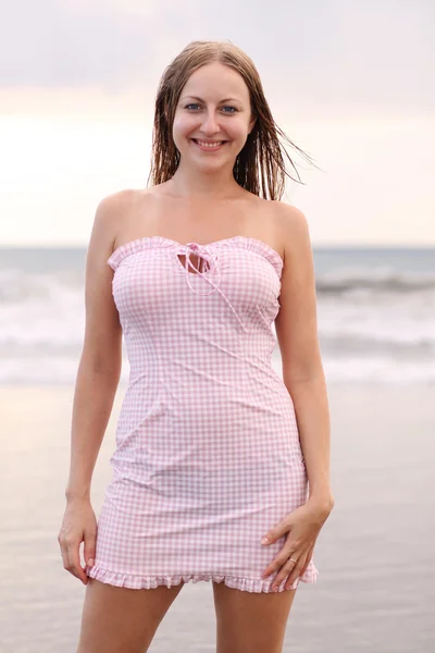 Mladá žena v růžových šatech na pláži — Stock fotografie
