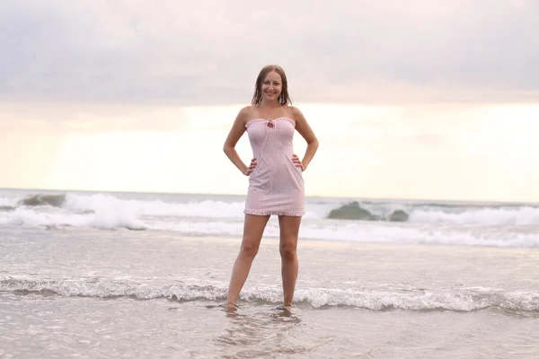 Jeune femme en robe rose à la plage — Photo