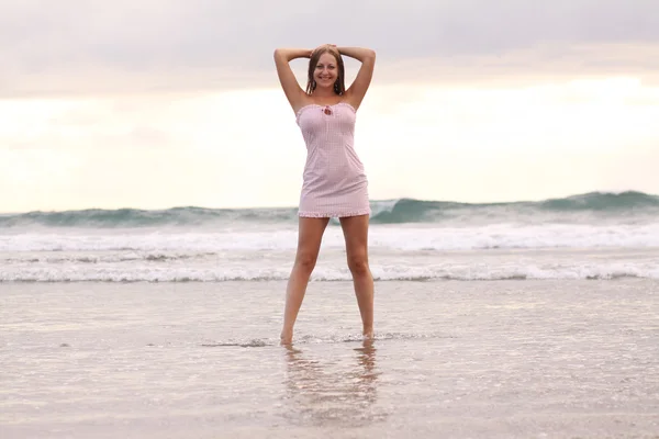 Jovem mulher de vestido rosa na praia — Fotografia de Stock