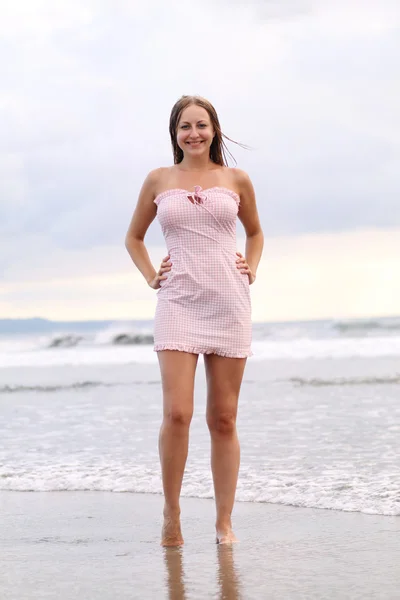Giovane donna in abito rosa in spiaggia — Foto Stock