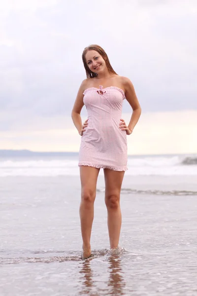 Jovem mulher de vestido rosa na praia — Fotografia de Stock