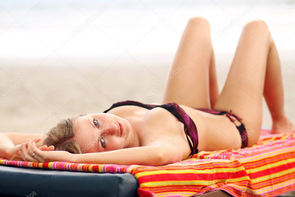 Woman sunbathes lying on chaise lounges