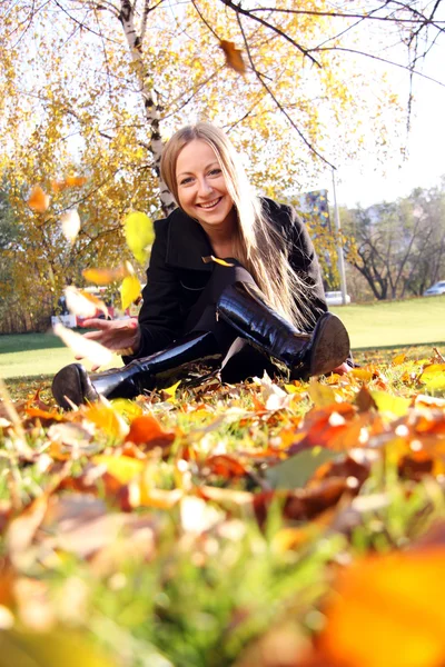 Woman sitting on a carpet of leaves in autumn park — Stock Photo, Image