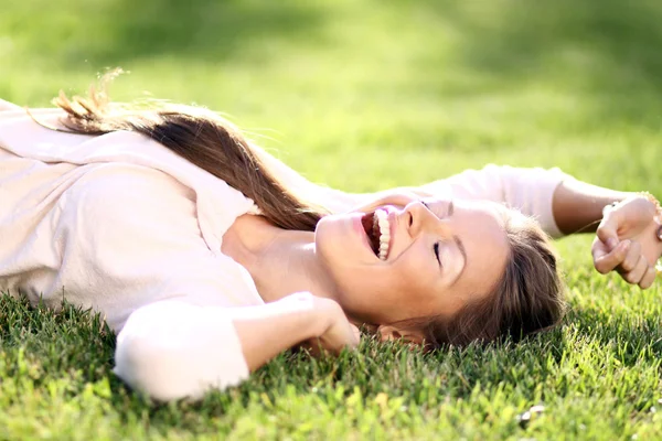 Roztomilá mladá žena leží na travnaté hřiště v parku — Stock fotografie