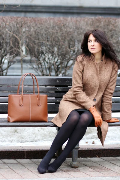 Beautiful young city woman sits on a bench — Stockfoto