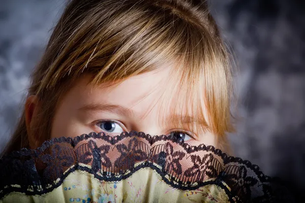 Meisje die betrekking hebben op haar gezicht met een lacy ventilator — Stockfoto