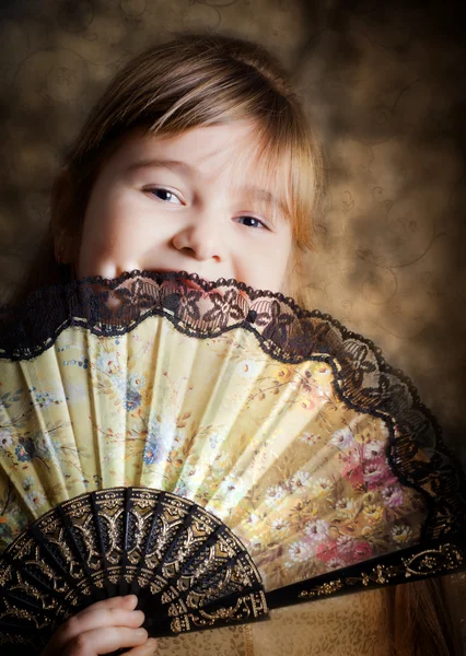 Dívka zakryla tvář s krajkovým ventilátor — Stock fotografie