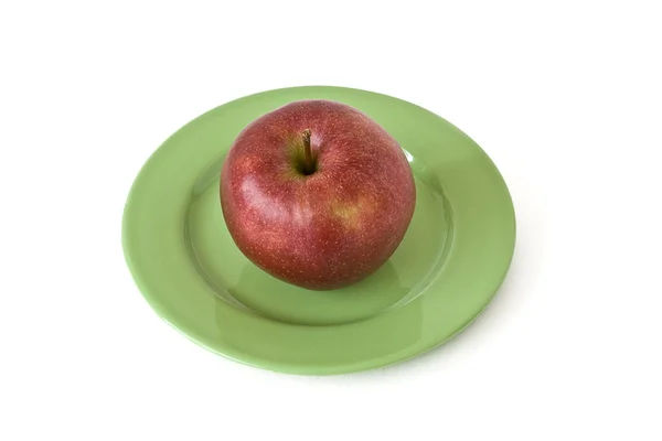 Czerwone jabłko na płytce zielony — Zdjęcie stockowe
